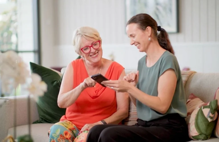 Two women use a property and resident app on a smartphone.